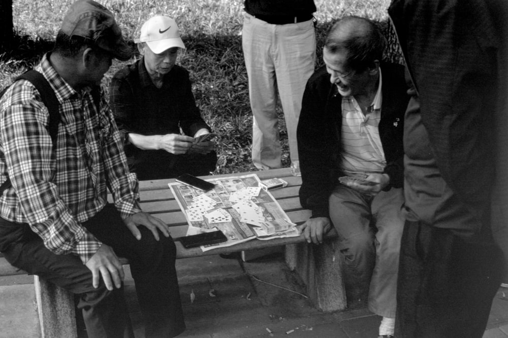 a group of men sitting around a wooden bench
