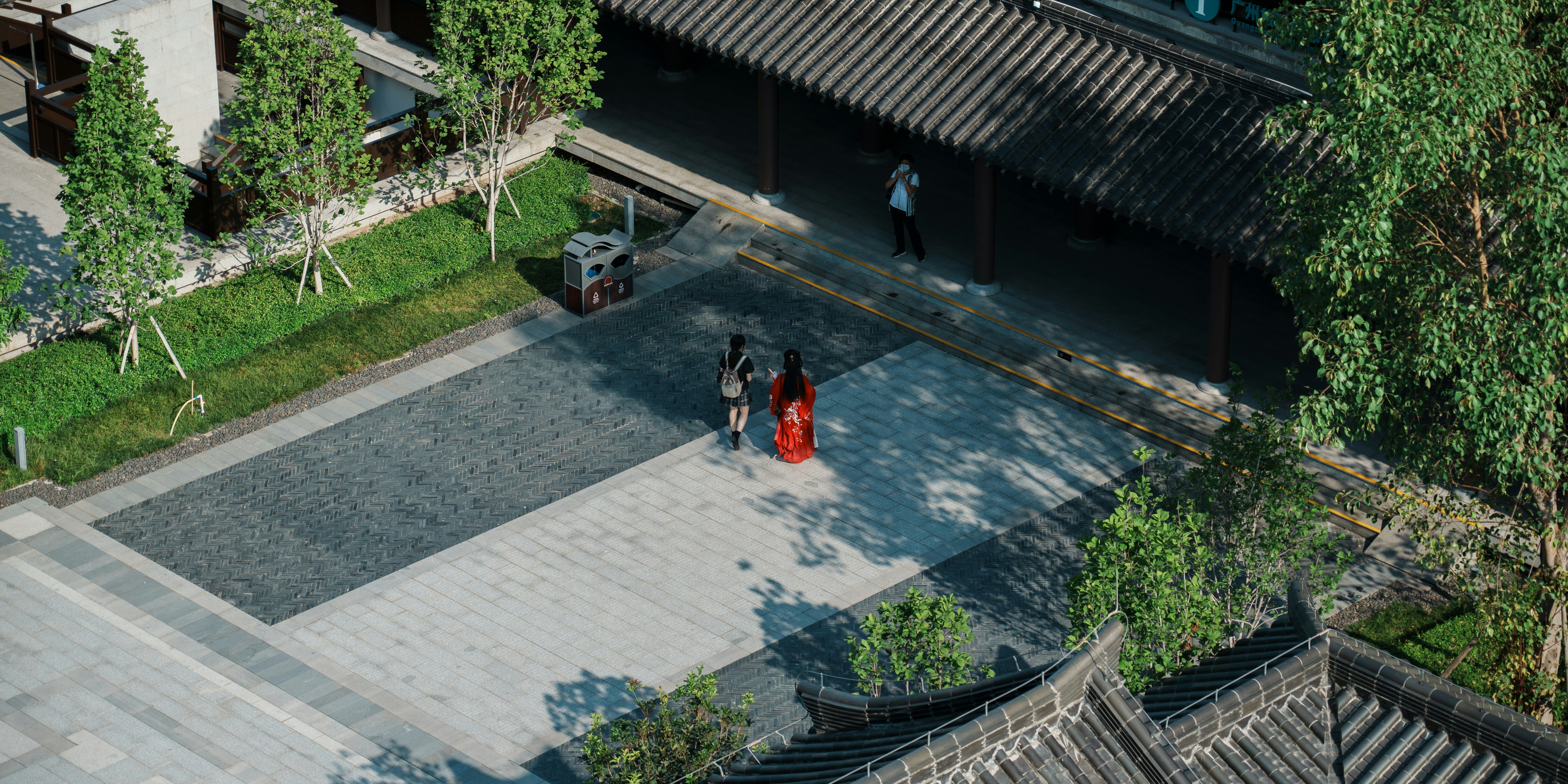 an aerial view of two people walking in a courtyard