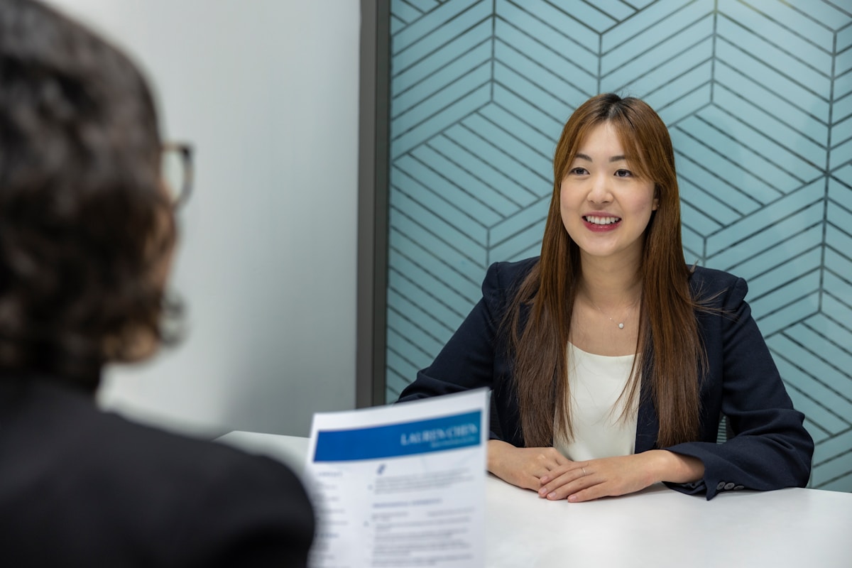 interviewer holding resume, speaking across table at candidate