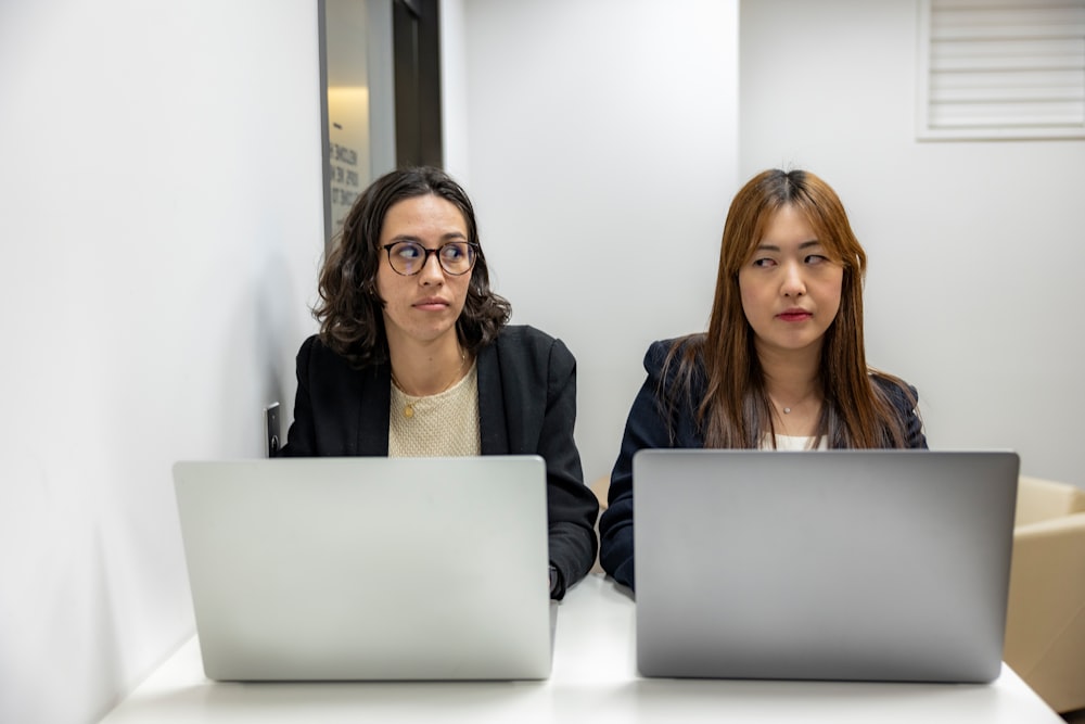 two women sitting at a table with laptops