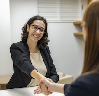 a woman shaking hands sitting at a table in a business setting