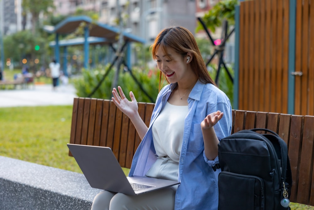 a woman sitting on a bench using a laptop