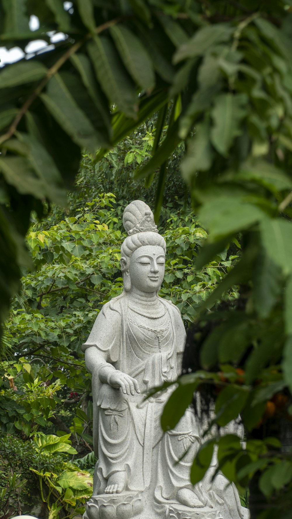 a statue of a buddha sitting in the middle of a forest