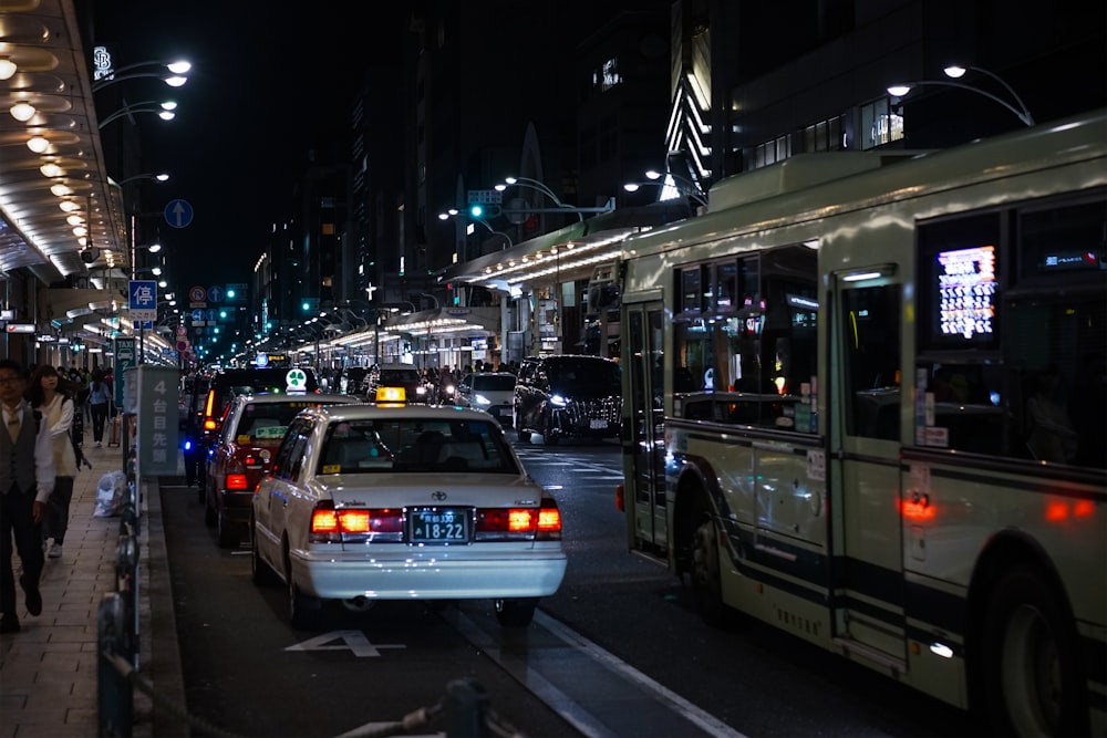 a busy city street at night with cars and buses