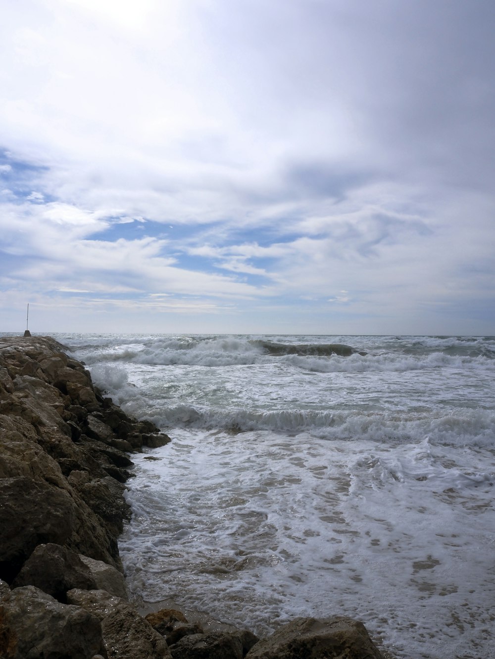 eine Person, die an einem felsigen Strand neben dem Meer steht