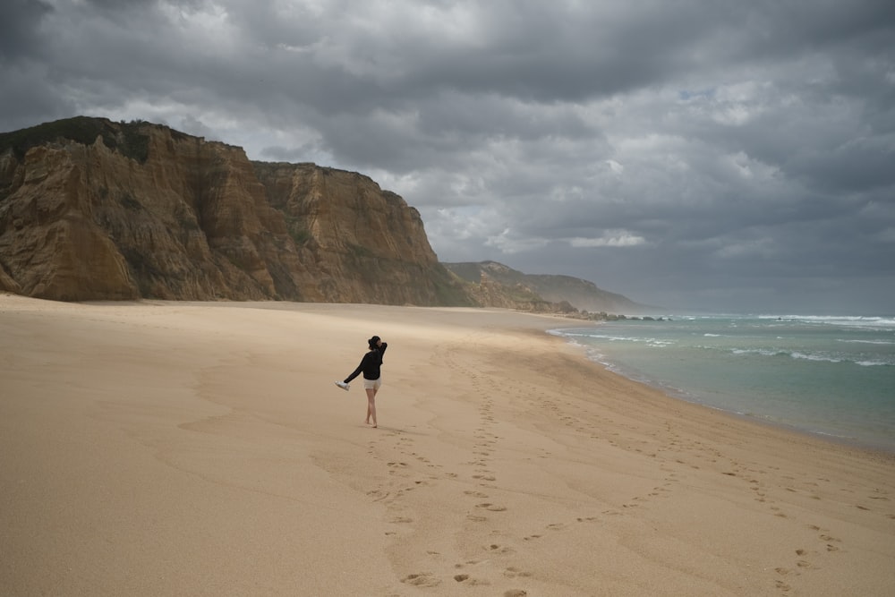 a person walking along a sandy beach near the ocean