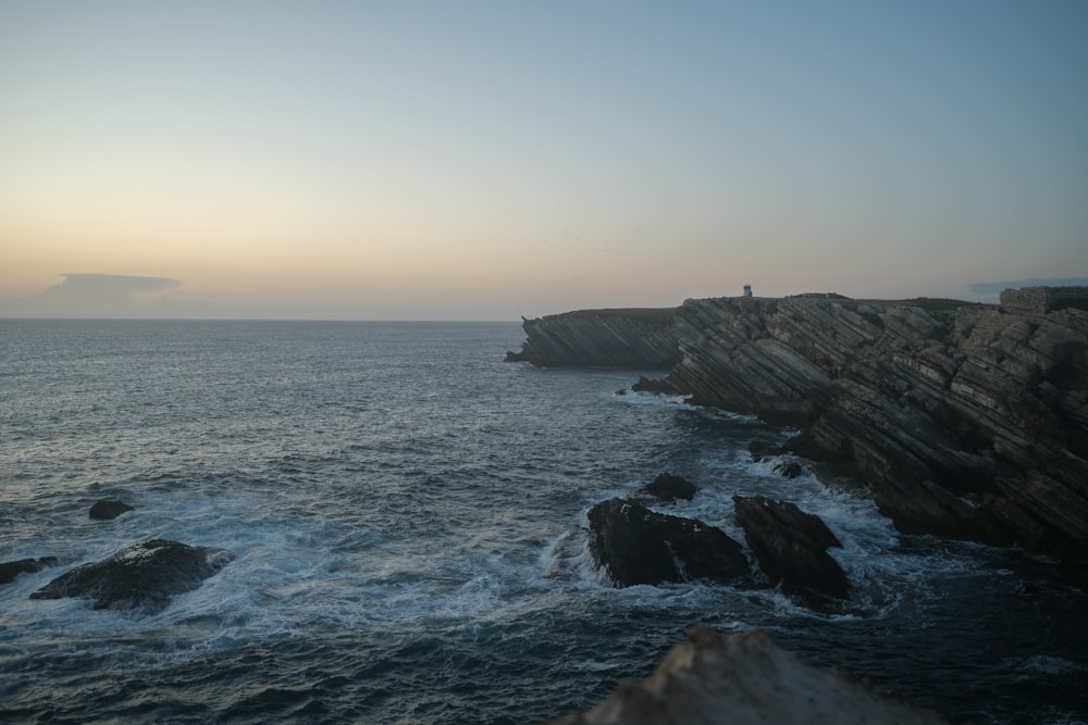 a person standing on the edge of a cliff near the ocean