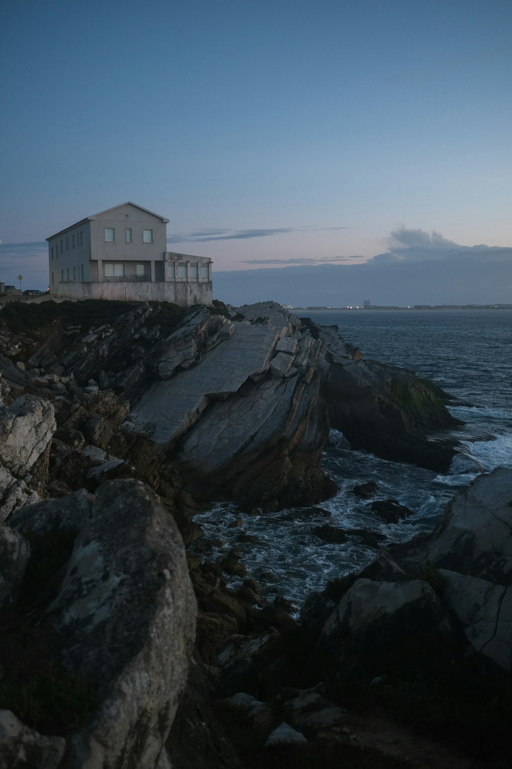 a house sitting on top of a rocky cliff next to the ocean