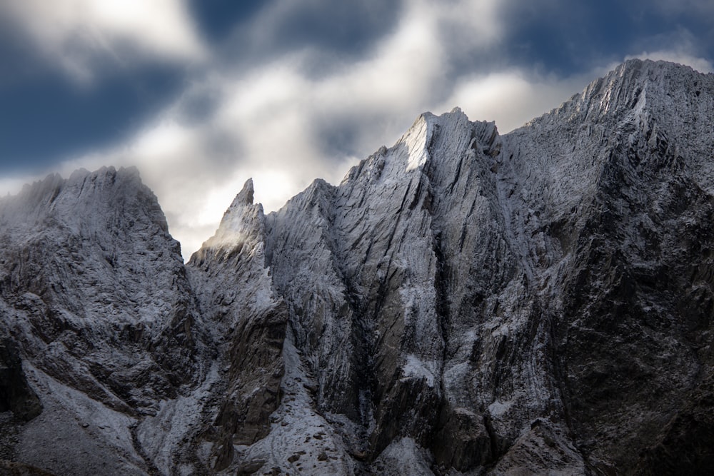 a snow covered mountain range under a cloudy sky