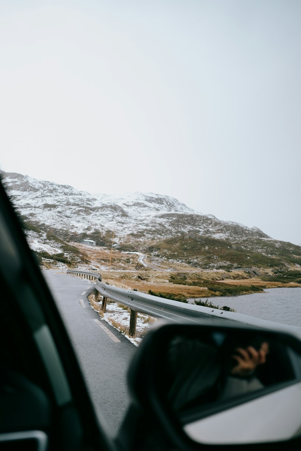 a car driving down a road next to a snow covered mountain