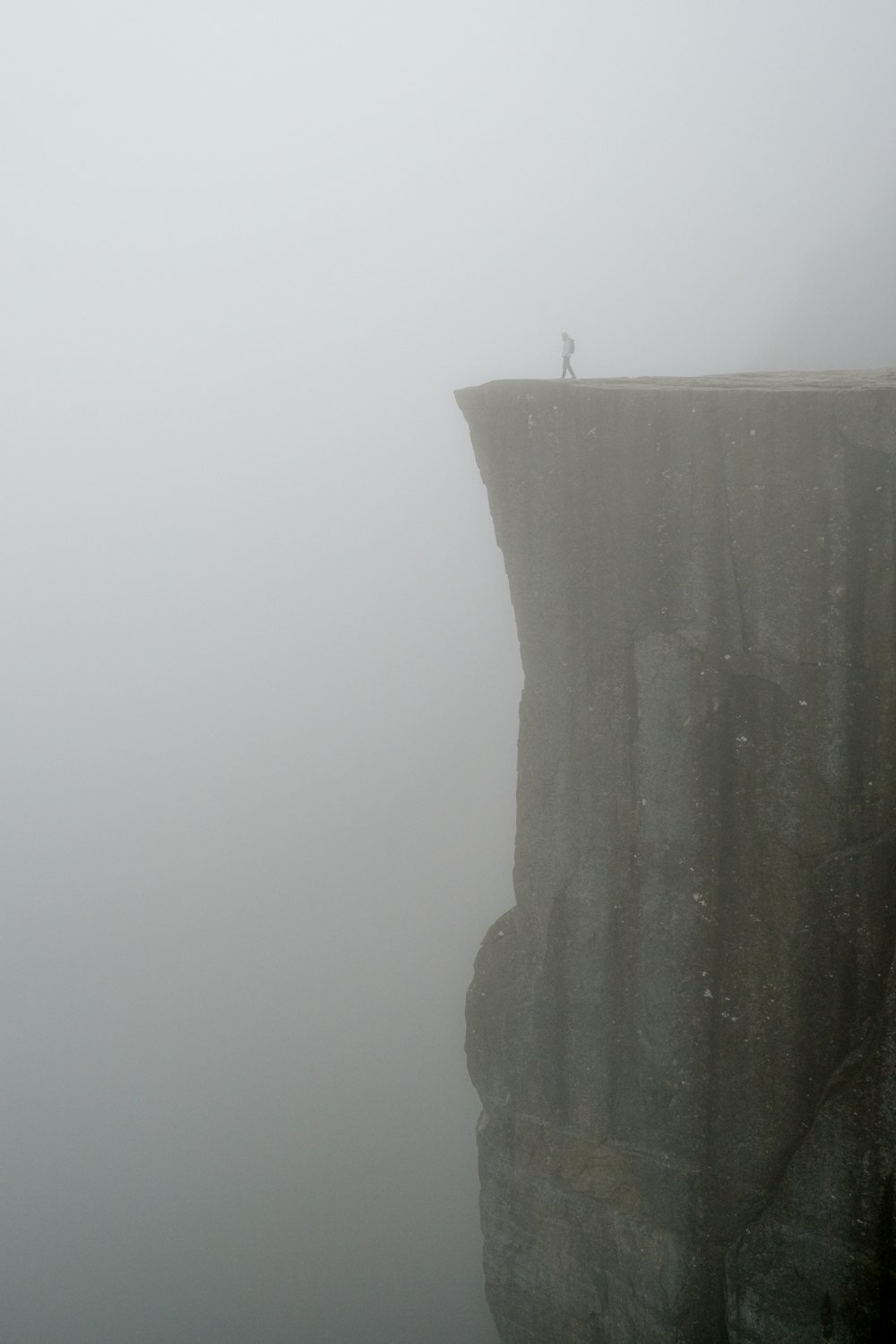 a person standing on top of a cliff in the fog