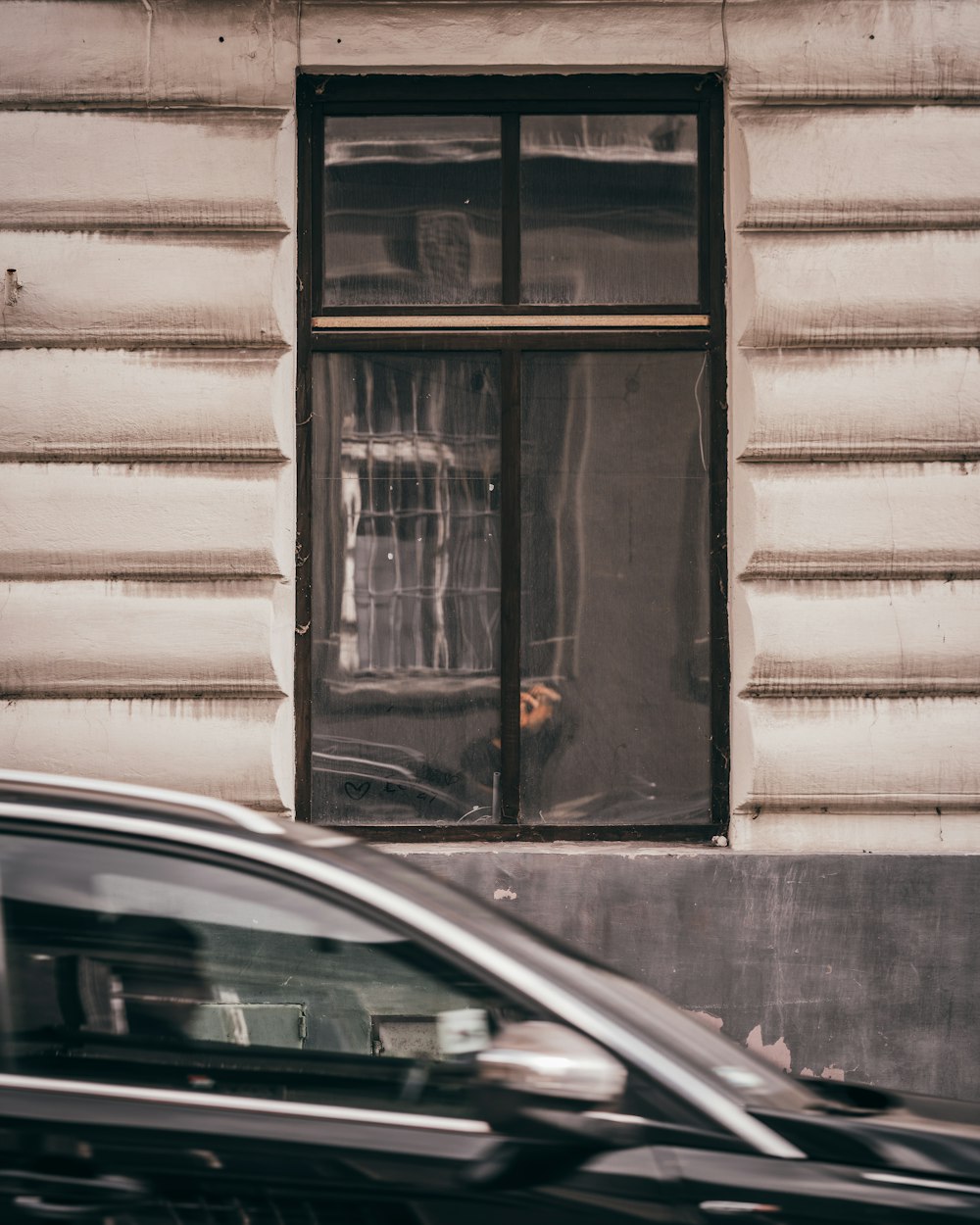 a black car driving past a tall white building