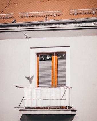A technician installing a custom pigeon net on a sunny balcony with cityscape in the background.