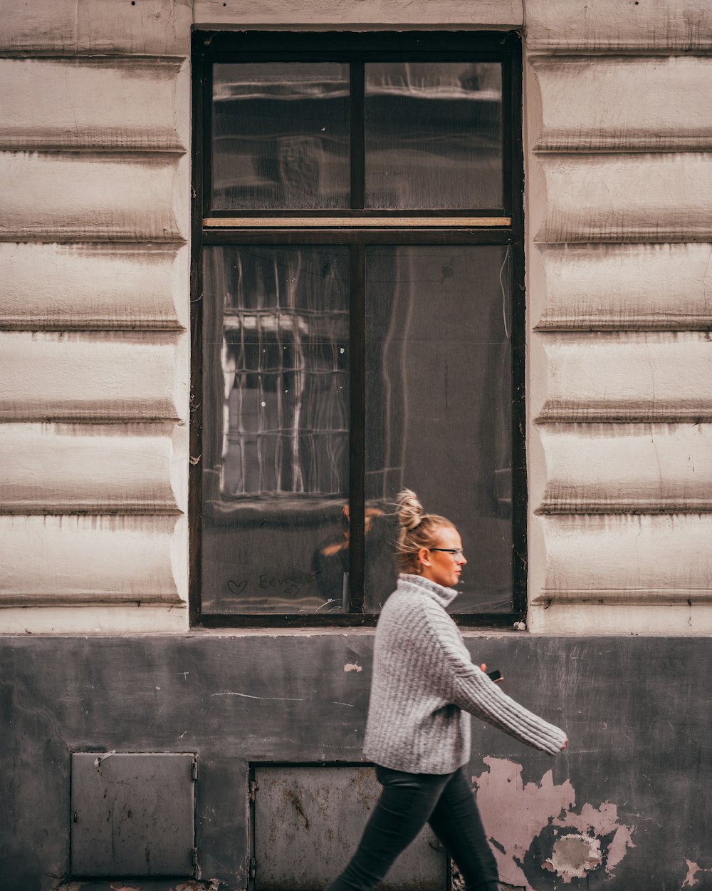 a woman walking down a street past a building