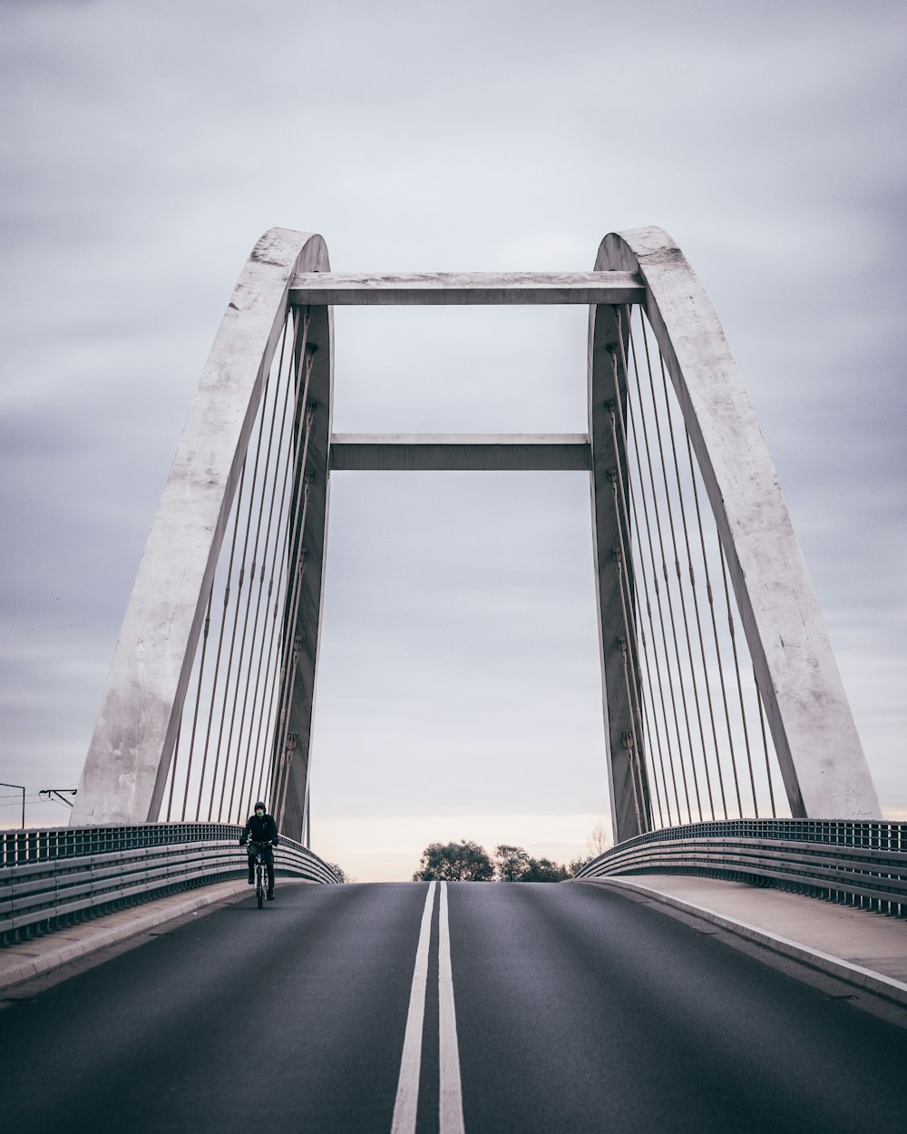 a man walking across a bridge on a cloudy day