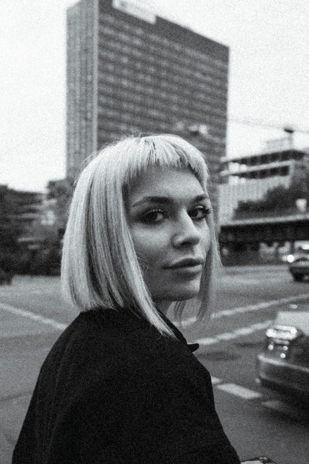 uma foto em preto e branco de uma mulher em uma rua da cidade