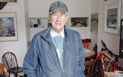 An older gentleman confidently walking with a custom-fitted walker in his cozy living room.
