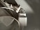 A close-up of two electrical plugs lying on a smooth surface. One plug is attached to a cable, while the other plug adapter is next to it. The image features a combination of shadows and light, highlighting the metallic prongs and white plastic casings.