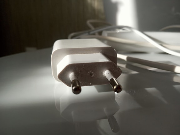 Close-up shot of a sleek, modern plug resting on a wooden surface, highlighting its smooth finish.