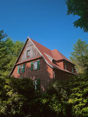 Cozy house with a red roof and garden under a clear blue sky.
