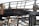 A close-up view of a charred metal structure. The metal beams and framework seem to have been severely damaged by fire. The surface of the metal is blackened and covered with soot, and parts of the structure appear to be twisted and melted.