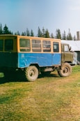 a blue and yellow truck parked in a field