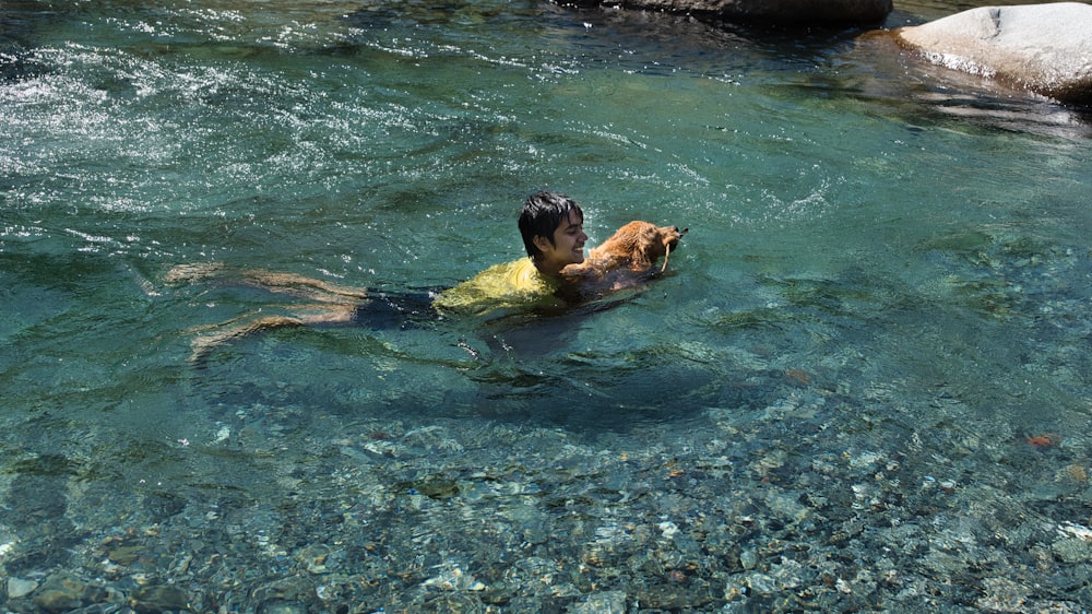 a man swimming in a river with a dog