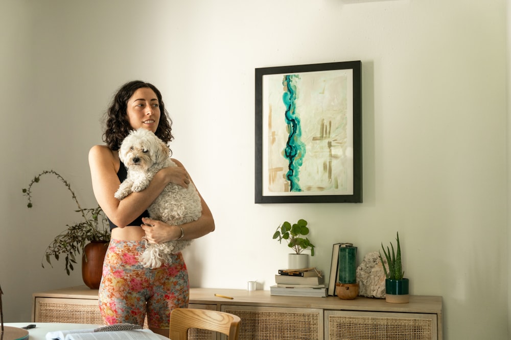 a woman holding a white dog in her arms