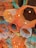 A complex and colorful ceiling installation composed of geometric wooden frames in orange, teal, and white hues. The arrangement includes exposed light bulbs embedded within the frames, along with a black speaker, adding an artistic and modern touch.