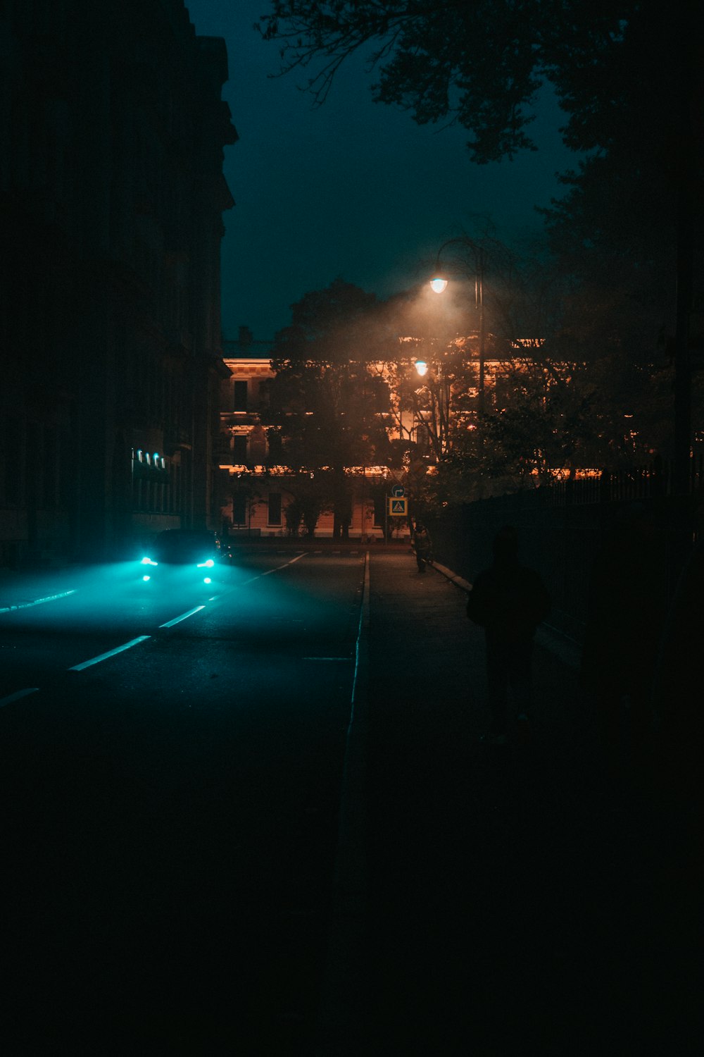 a dark street at night with a person walking down the street