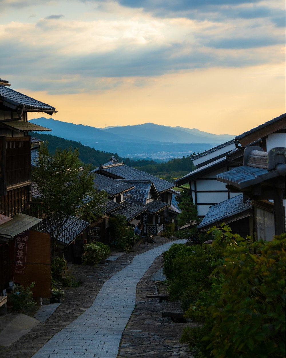 a narrow street with buildings and mountains in the background