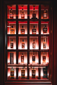 A cozy tasting room with wooden shelves lined with whisky bottles and guests savoring samples.