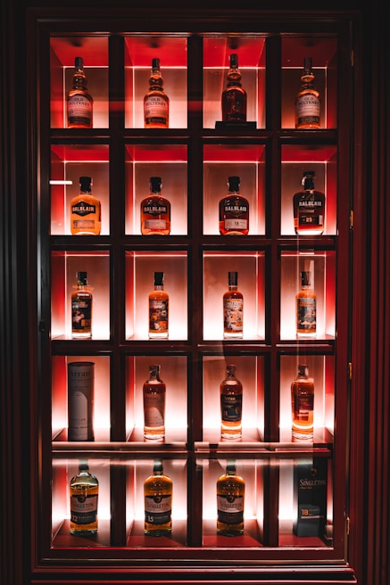 A wooden shelf showcasing an array of elegantly bottled rare whiskies from around the world