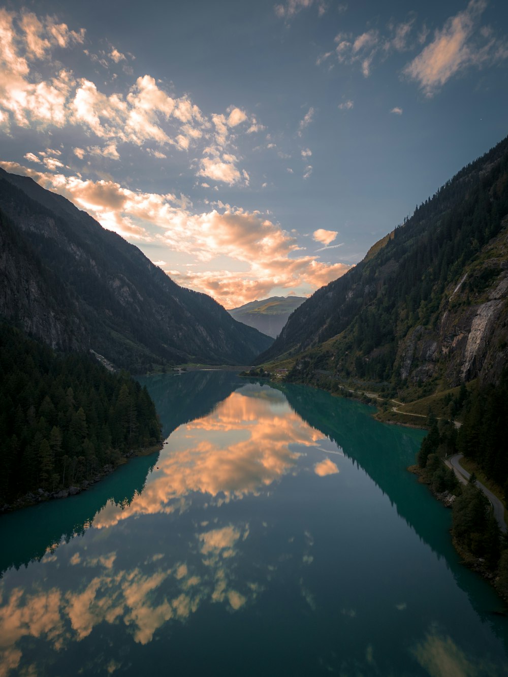 a body of water surrounded by mountains under a cloudy sky