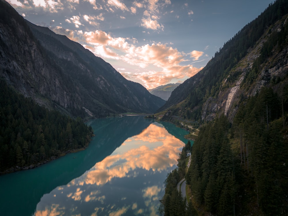 a lake surrounded by mountains under a cloudy sky