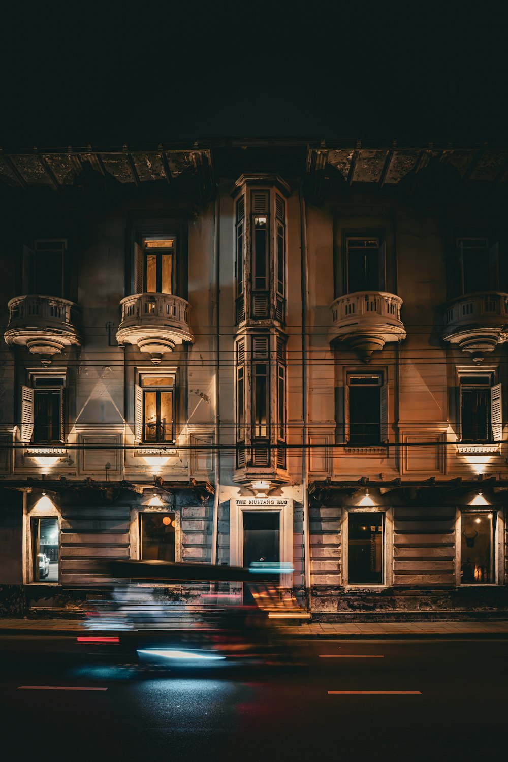 a car driving past a tall building at night