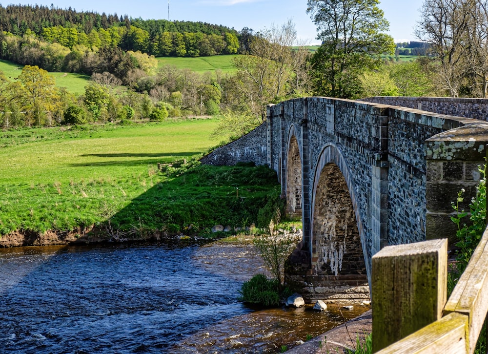 a stone bridge over a river in a green valley