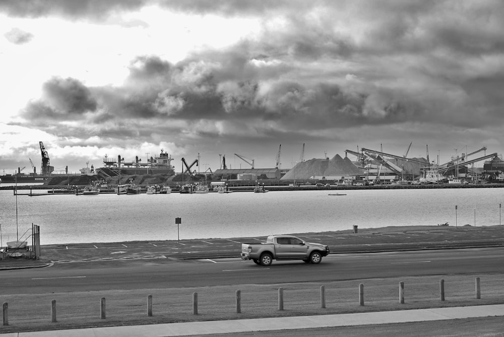 a truck driving down a road next to a body of water