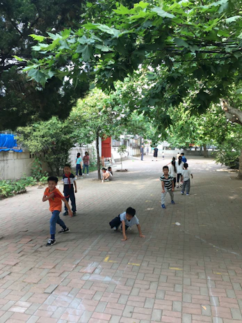 A group of children playing a lively game of tag on a green playground.