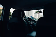 Close-up of a chauffeur’s hand on the steering wheel, with a city skyline in the background.
