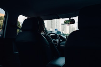 A driver assisting a passenger into a car on a city street.