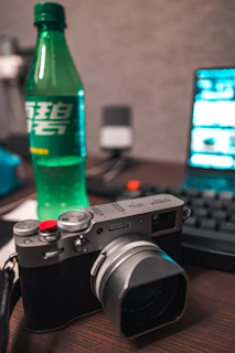A matte forest green notebook and camera resting on a crisp parchment-colored desk during a photo shoot.