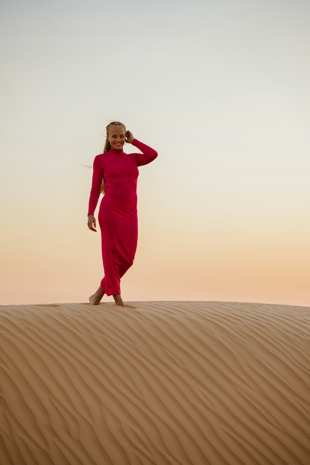 a woman in a red dress walking across a desert