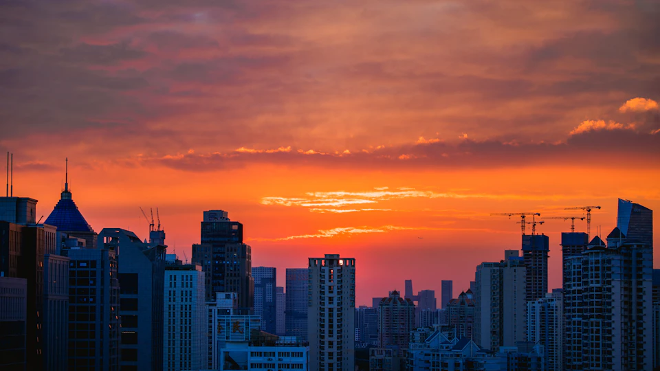City skyline at sunset with warm glow from setting sun behind tall buildings