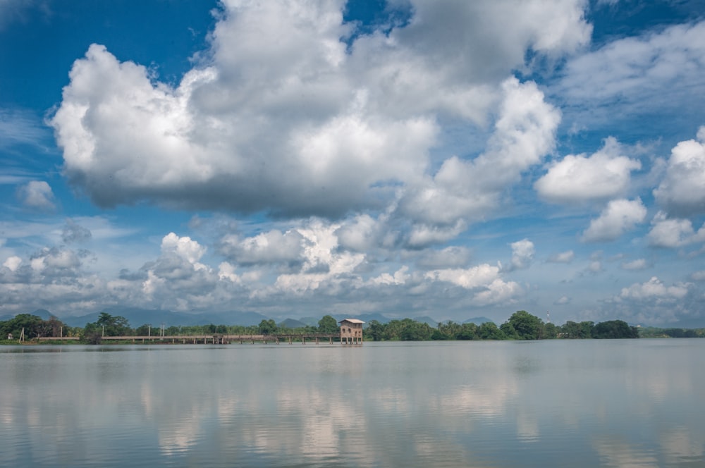 a large body of water surrounded by trees and clouds