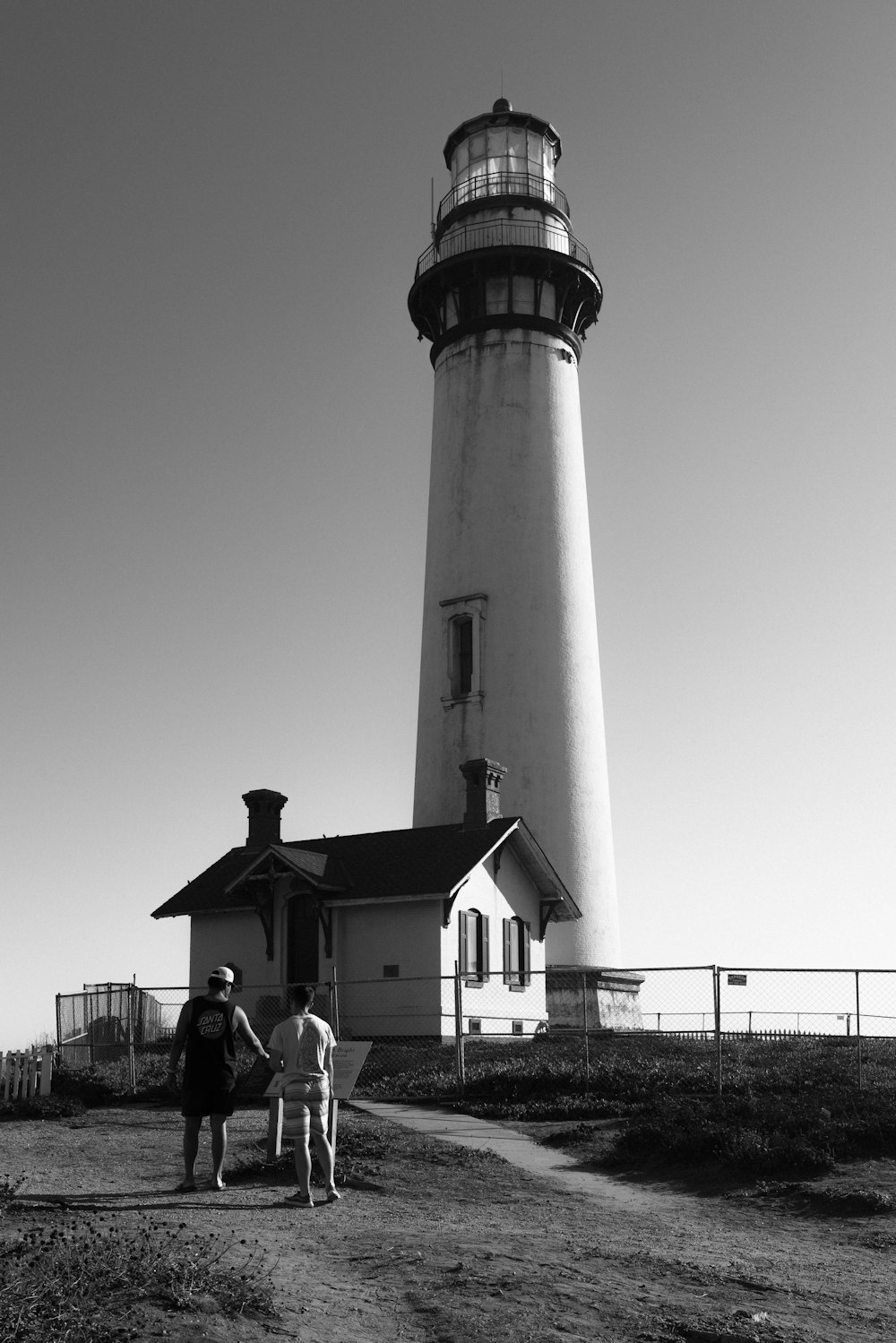 a couple of people standing in front of a light house