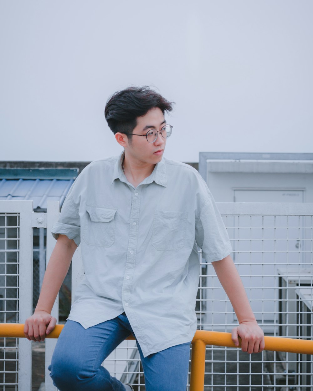 a young man leaning on a yellow rail