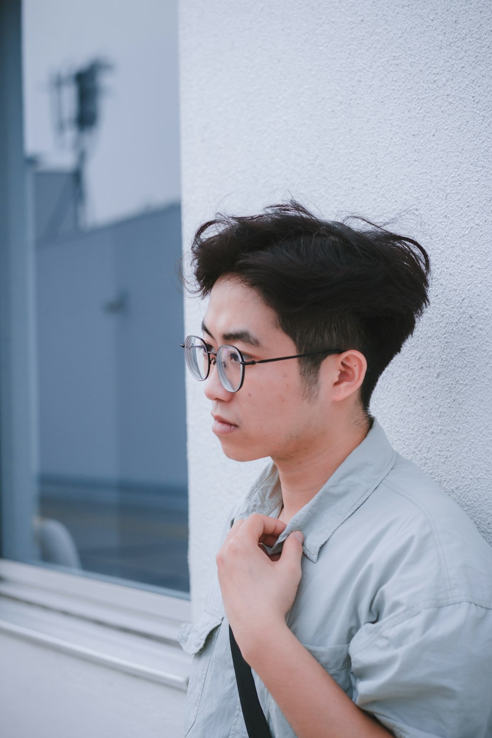 a man with a tie and glasses standing next to a building