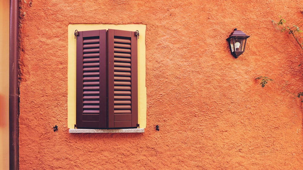 a red building with a window and a lamp on the side