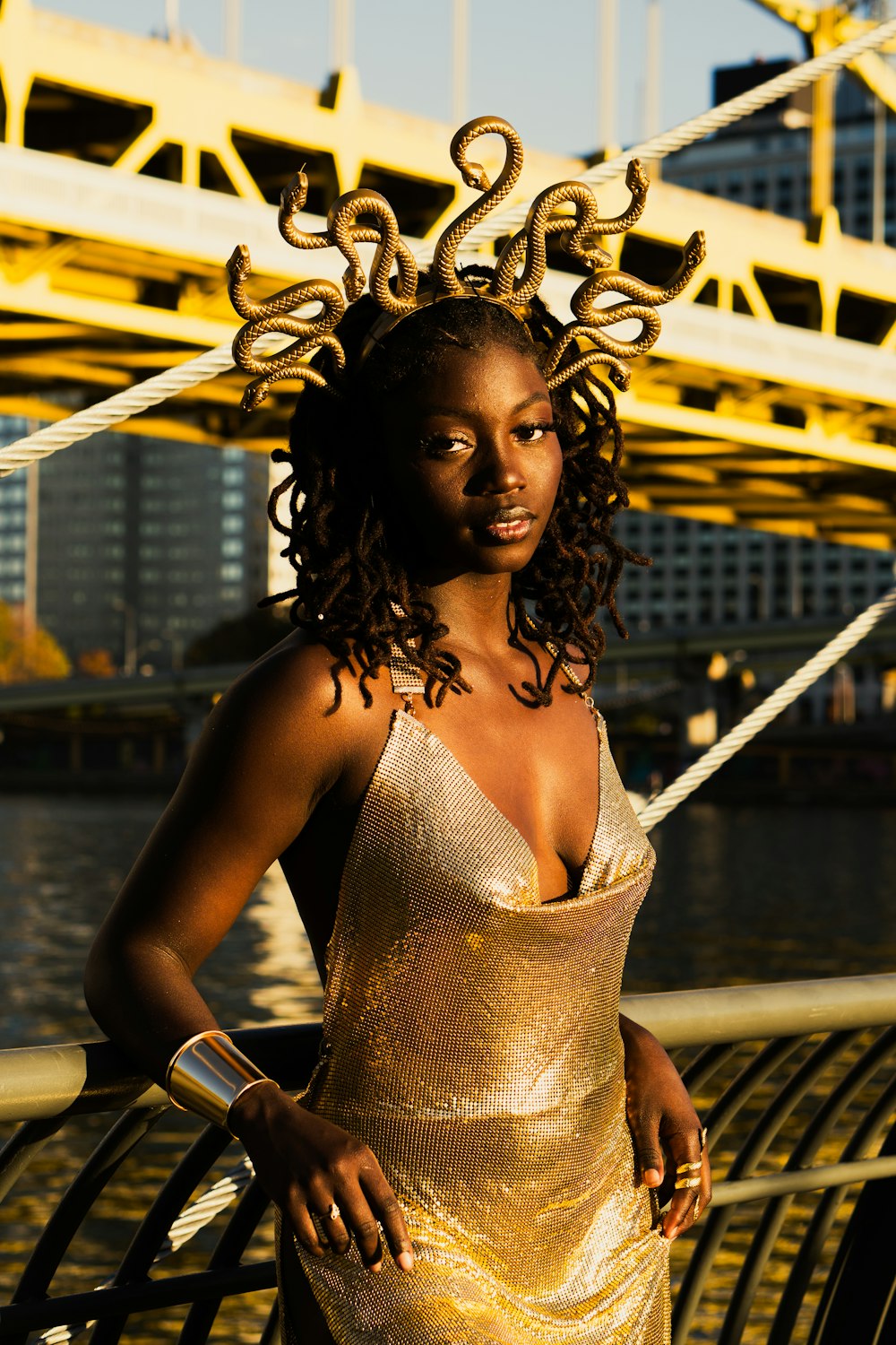 a woman in a gold dress standing on a bridge